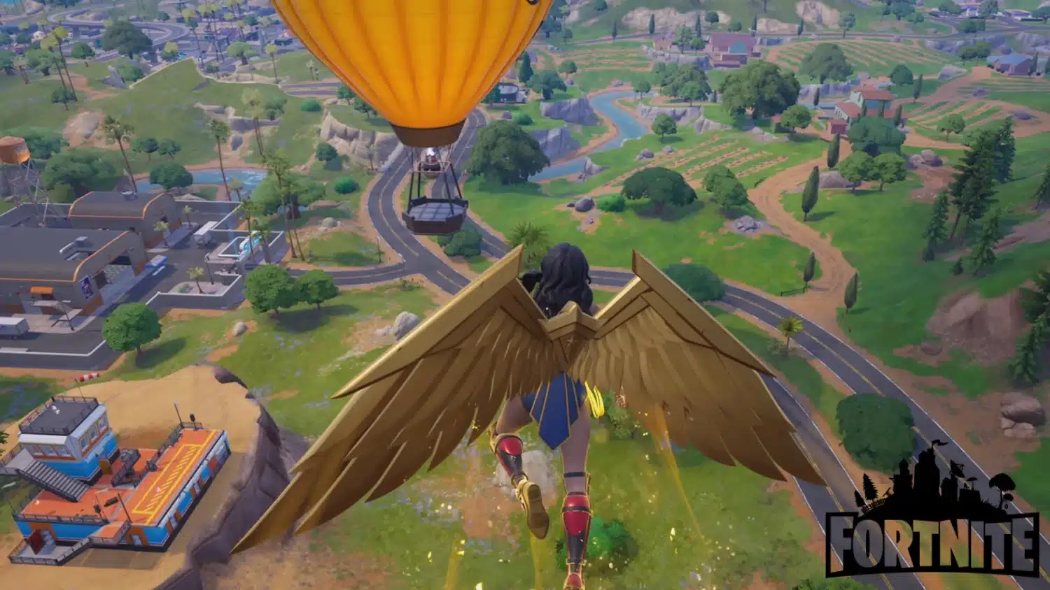 Wonder Woman with large gold wings descending over a green Fortnite landscape featuring roads, buildings, and farms