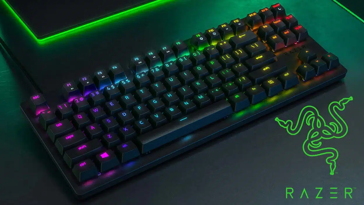 razer huntsman tournament edition gaming keyboard with multicolor keys and green logo on the right side on a dark desk surface