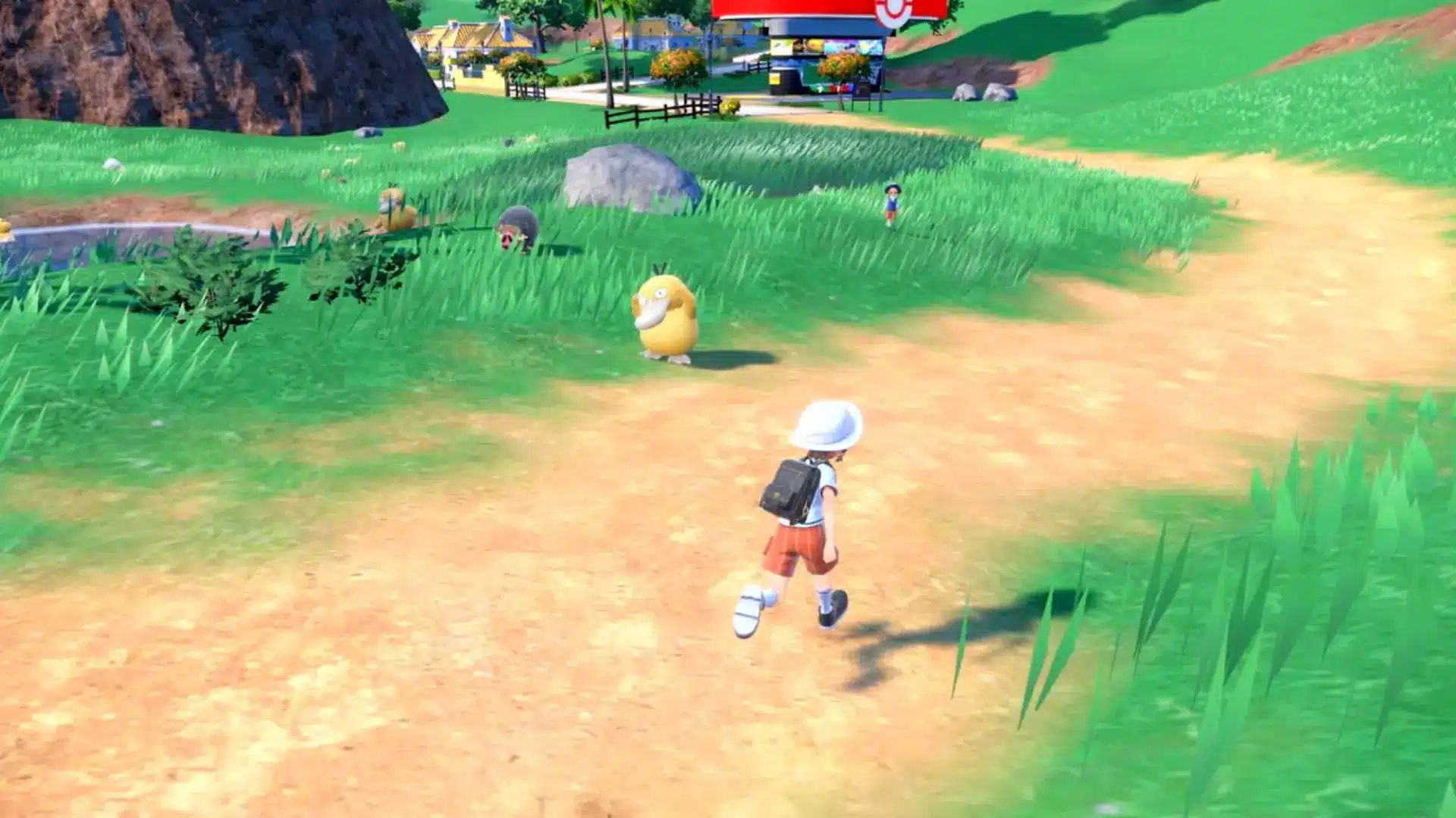 Player walking in grassy open area with wild Pokémon visible, small village in distance, sunny environment in Pokémon Scarlet