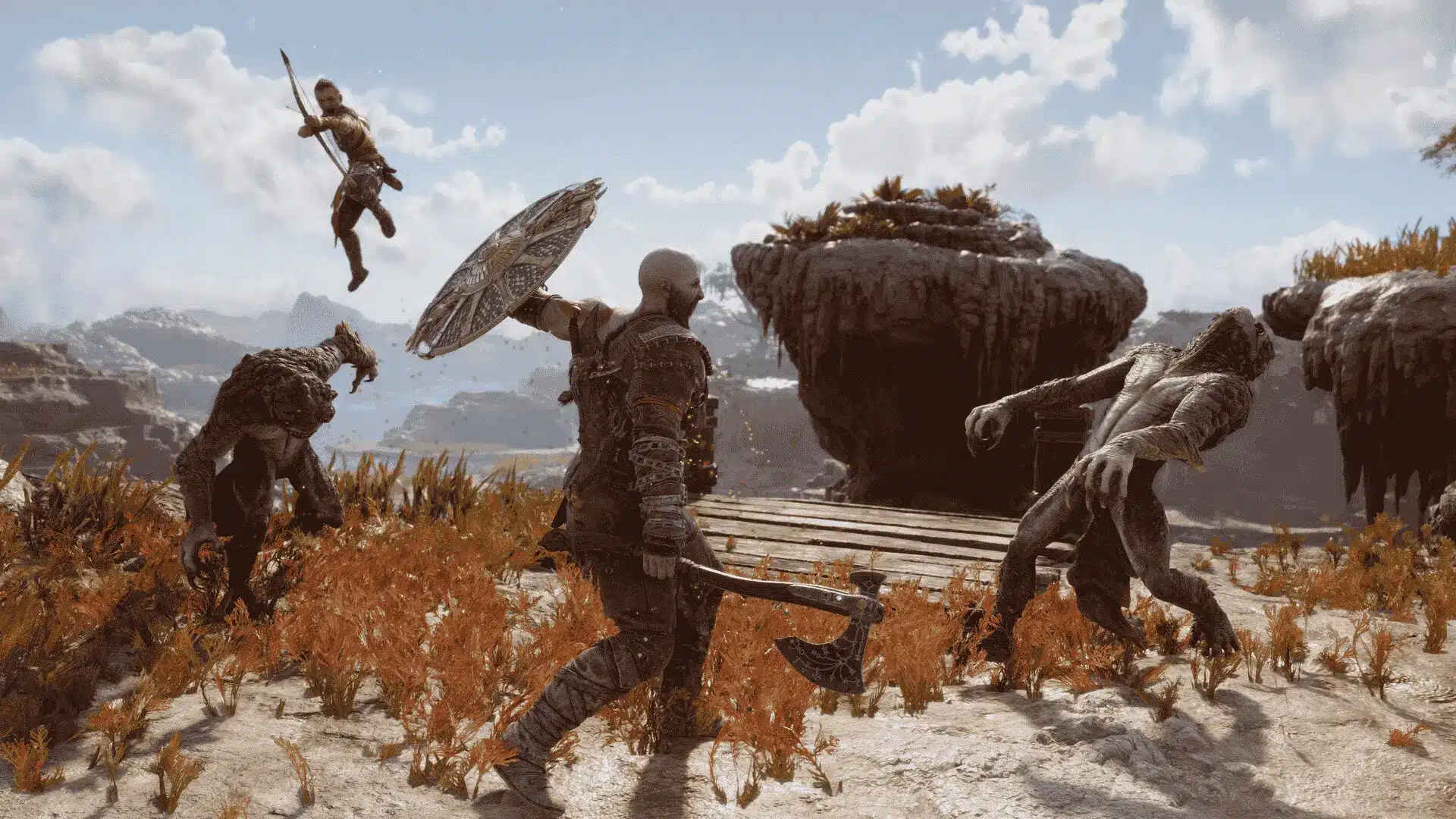 Kratos blocks an enemy attack with his shield while Atreus leaps, showing dynamic combat evolution in action.