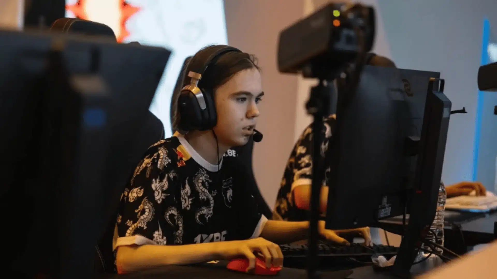 Esports player using gaming monitor, keyboard, mouse, and headset at a tournament setup