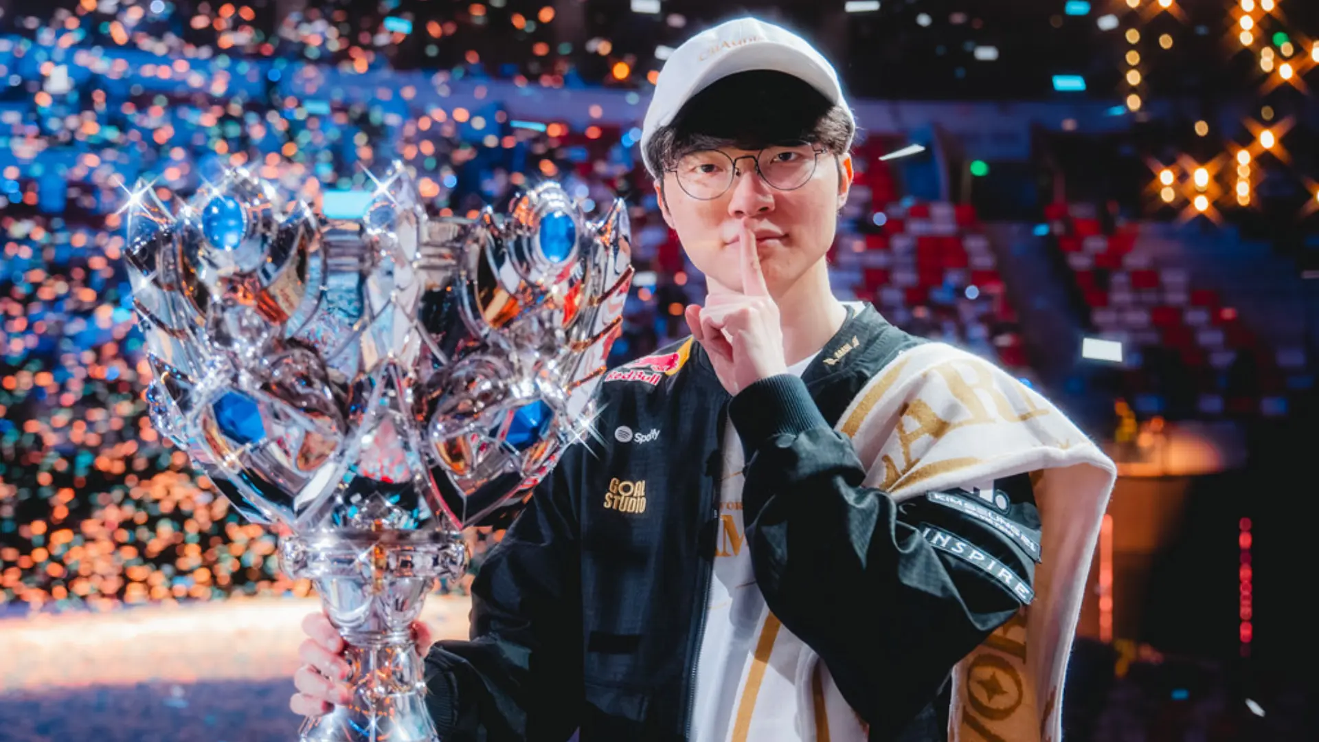 League of Legends player Faker holding the Worlds trophy on stage after winning a championship title.