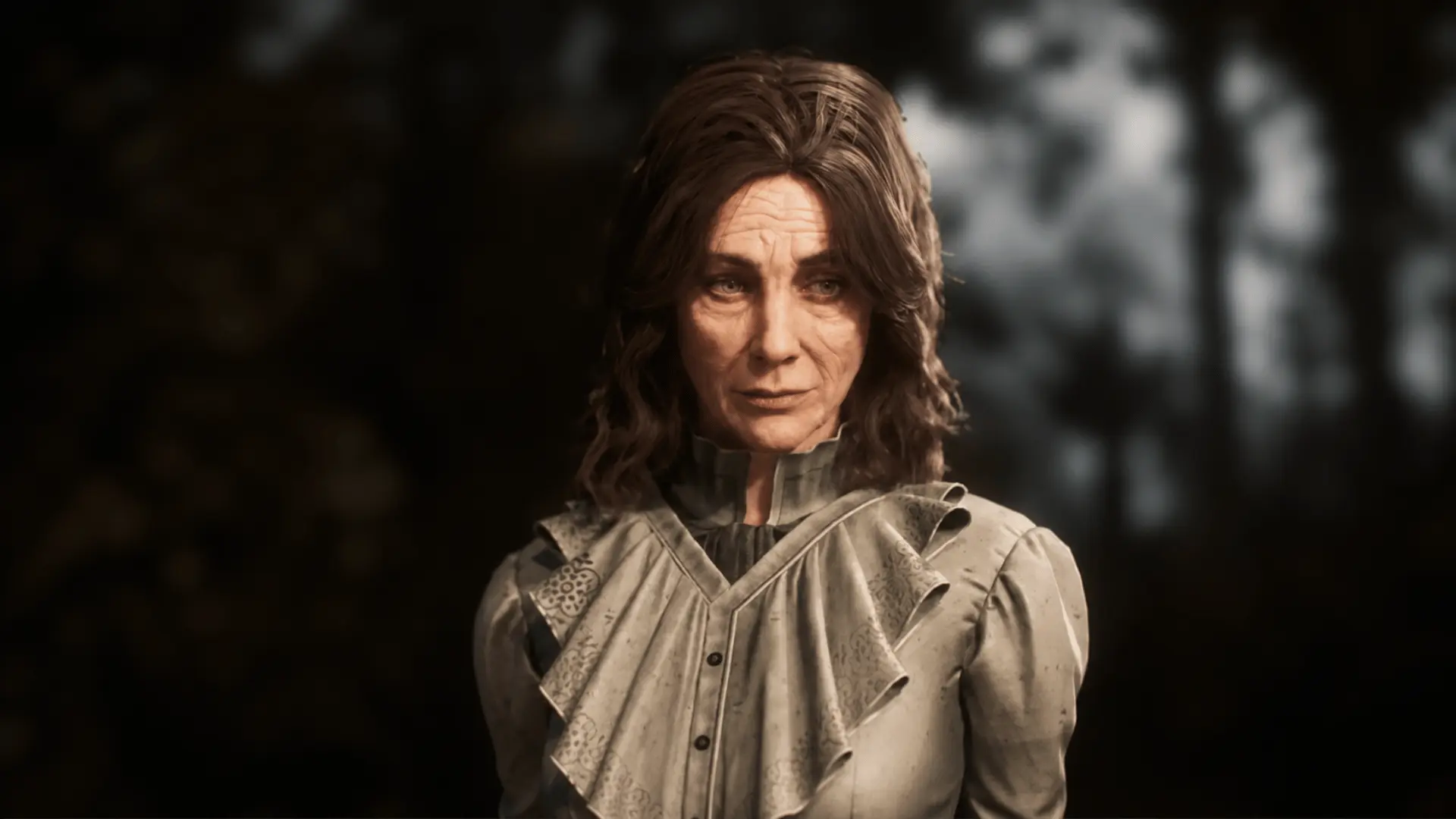 Aline Dessendre with shoulder-length brown hair wearing a light ruffled high-collar outfit against a dark blurred background.