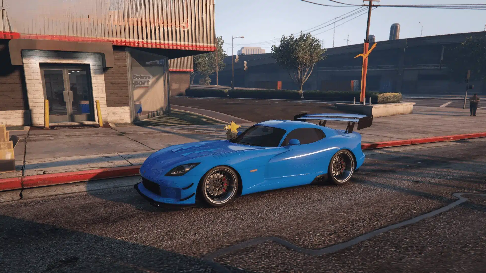 Blue Bravado Banshee GTS with a large rear wing parked outside Premium Deluxe Motorsport in GTA Online