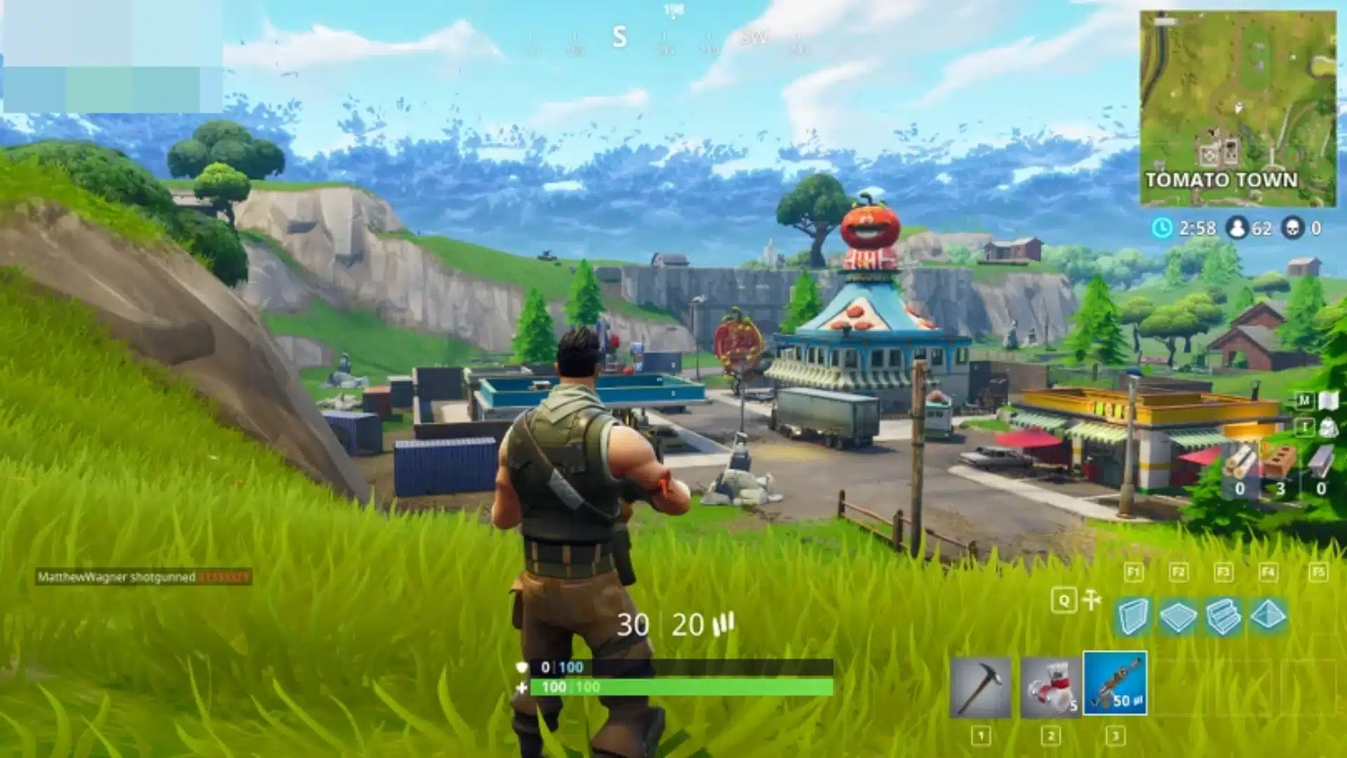 Armed Fortnite character overlooks Tomato Town from a grassy hill during battle