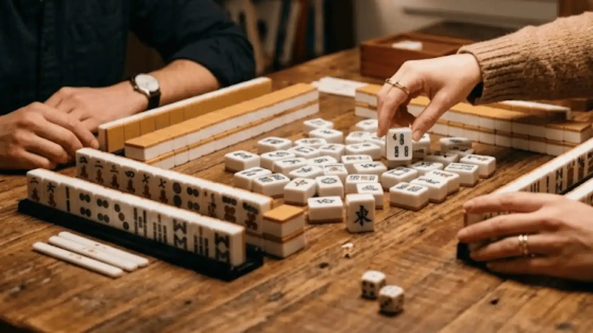 Two players playing Mahjong with four racks and a center tile pile in a focused two-player setup.