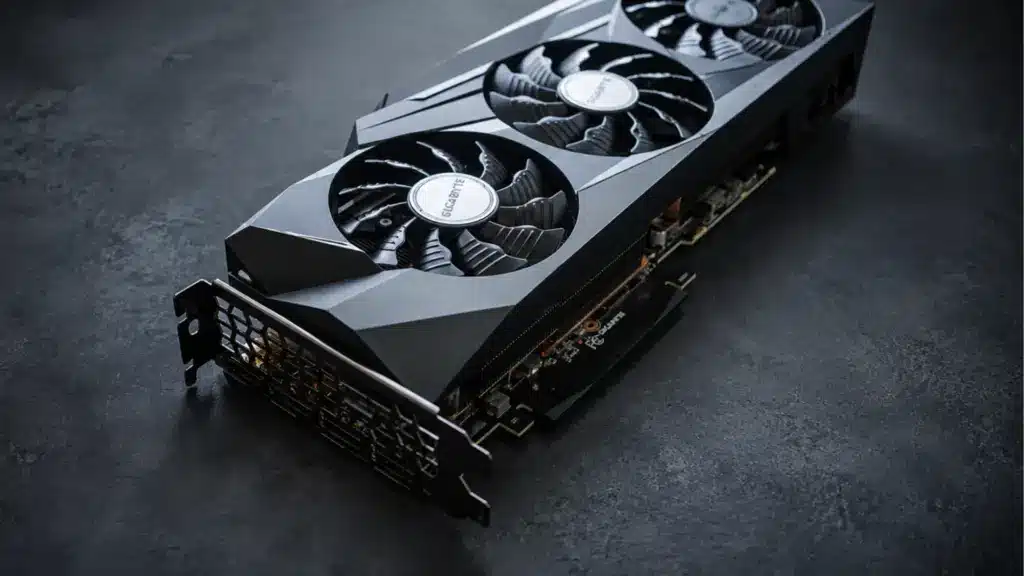 Black triple-fan graphics card on a dark textured surface under cool studio lighting