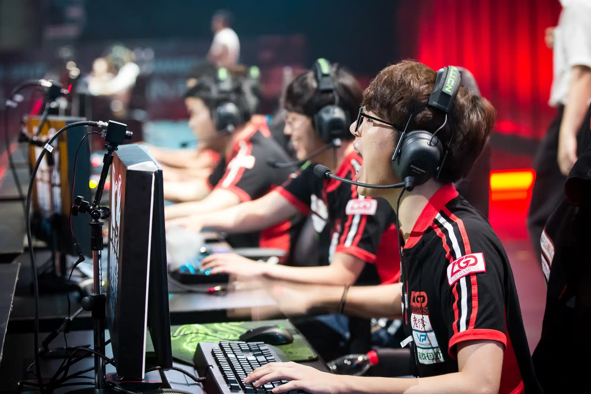 Pro esports players competing at a live tournament, focused on screens in a professional gaming arena.
