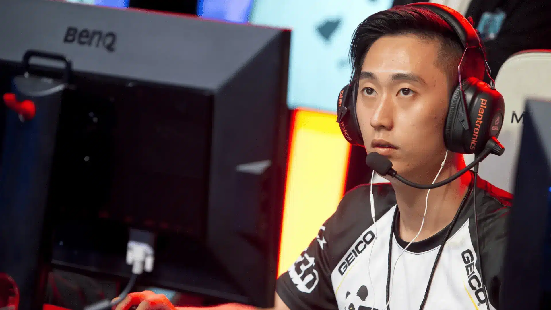 Esports player Psalm looks intently at his monitor while wearing a headset during a competitive gaming tournament.