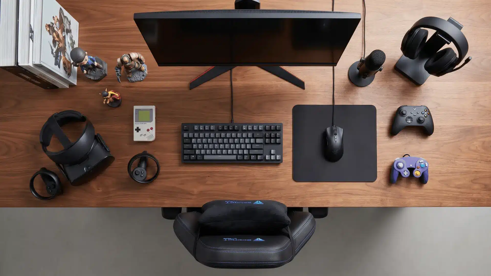 Top-down view of various gaming gadgets including monitors, peripherals, chairs, VR headset, and collectibles