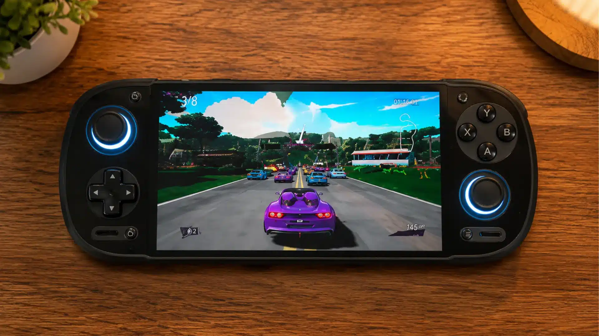 Black handheld console displays a colorful racing game on a warmly lit wooden desk