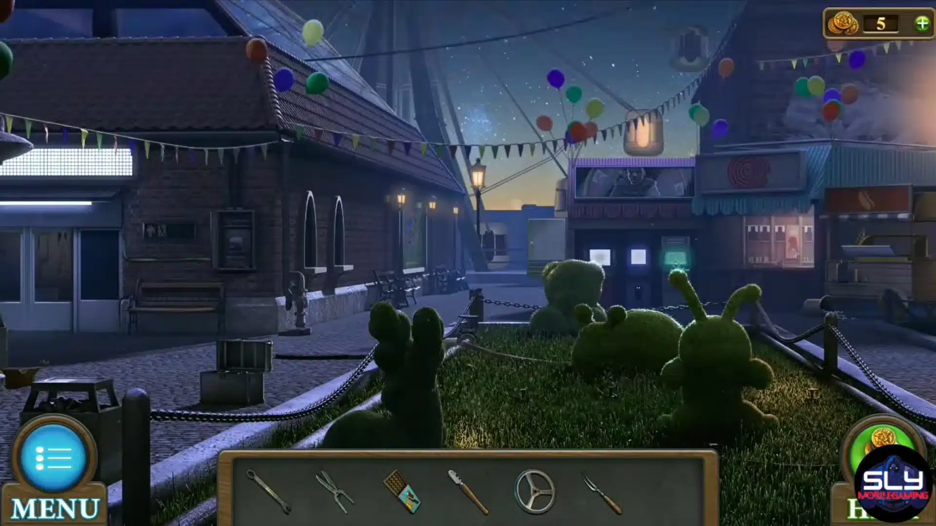An outdoor amusement park walkway at night featuring topiary figures and colorful festive flags.